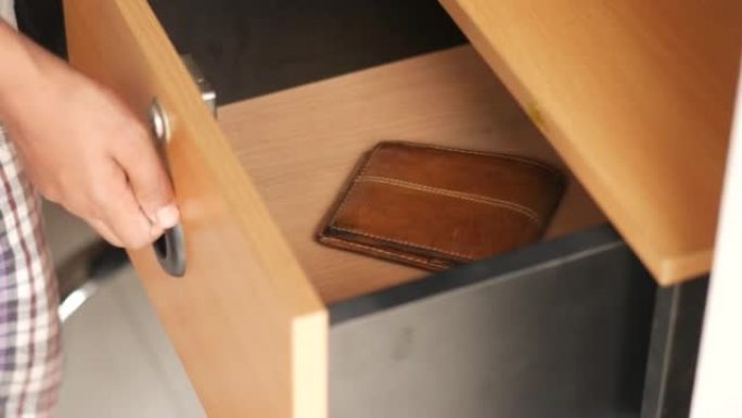男人的手打开橱柜里的木制抽屉，挑选一个钱包