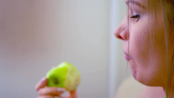 美女金发女人在沙发上吃青苹果