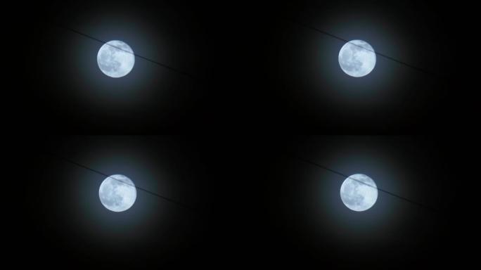 满月在夜空中移动。月光照在黑色的夜空中。夜城的电线