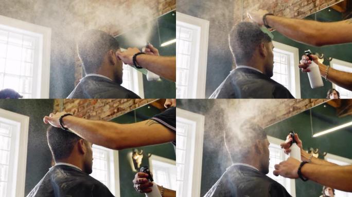 理发店里的理发师用喷雾瓶喷洒男士头发
