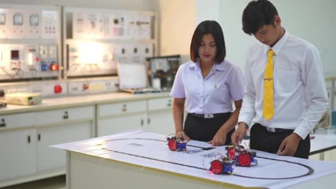 亚洲学生在实验室测试在路线上运行的机器人机器人汽车，并带有传感器响应。建筑师设计电路和会议共享技术思