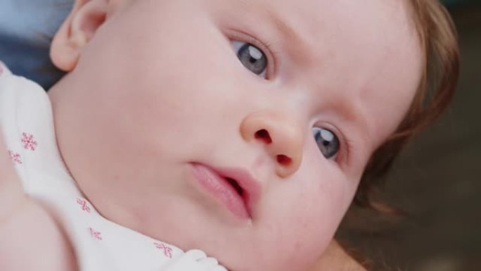好奇的高加索人可爱的小婴儿的特写脸肖像，蓝色的大眼睛在父亲的怀抱中环顾四周。欢迎来到世界概念
