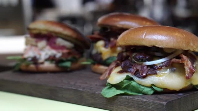 奶酪汉堡和海鲜汉堡配新鲜蔬菜在木板上选择性聚焦