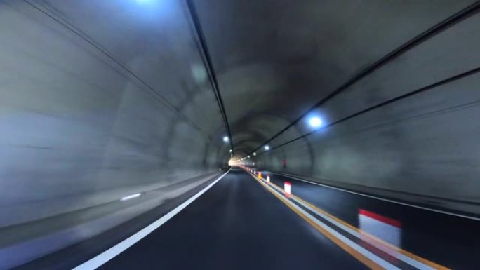 开车穿过高速公路隧道。高速公路双向隧道入口。隧道尽头的光