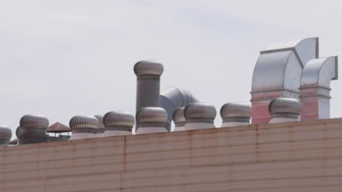 通风涡轮机在工厂屋顶上旋转，并带有白云。工业球呼吸机在白天旋转。