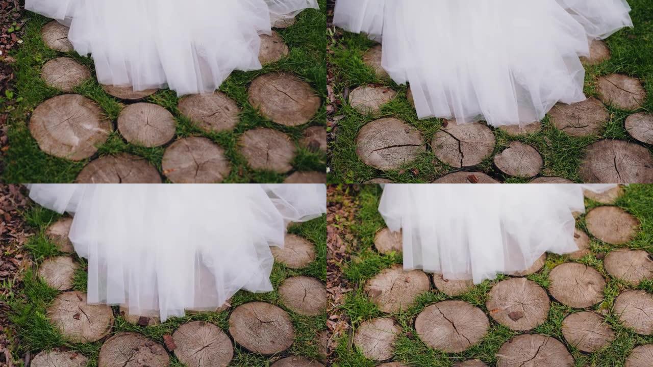 白色连衣裙的下摆在原木路面上滑动。相机拍摄了这件衣服的特写镜头