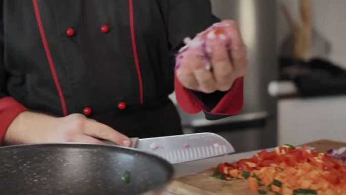 厨师将少量切碎的红洋葱放入煎锅中