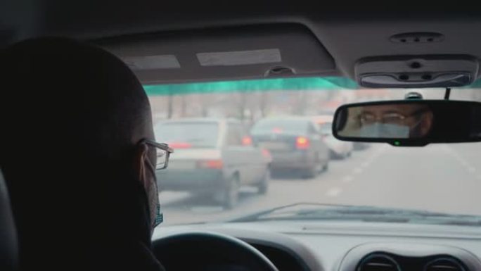 中年男子戴着医用口罩，上班时忙着开车