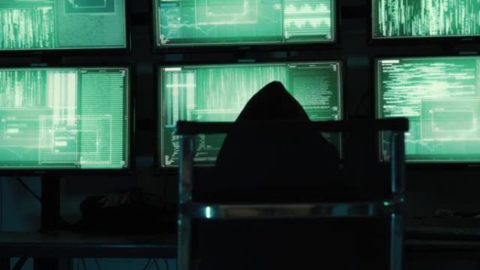 一个黑客程序员穿着连帽衫和黑色黑客面具隐藏自己的身份，用电脑进行黑客攻击，黑暗互联网的概念