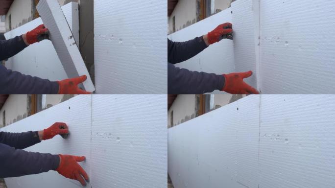 建筑工人在房屋外墙上安装聚苯乙烯泡沫塑料隔热板以进行热保护