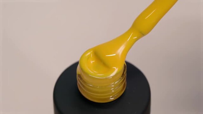 凝胶抛光黄色厚纹理。清漆从刷子流入黑管