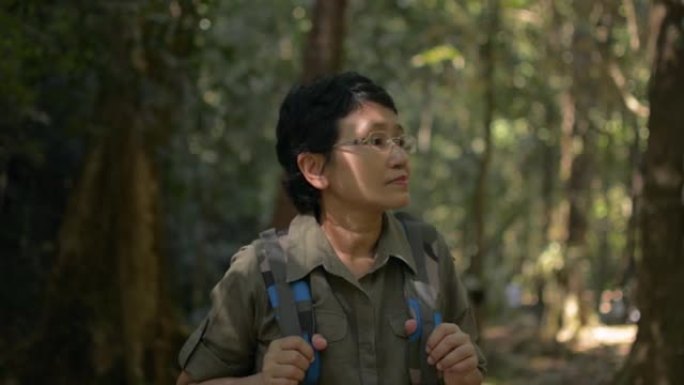 亚洲女性徒步旅行者的肖像与背包欣赏美丽的环境在热带雨林在夏天。