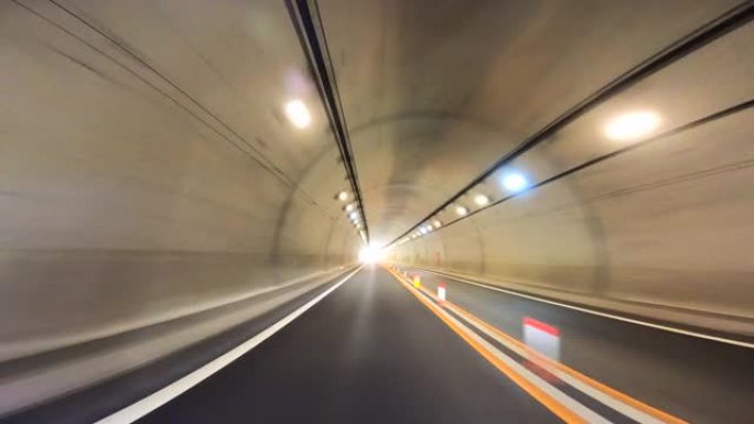开车穿过高速公路隧道。高速公路双向隧道入口。隧道尽头的光