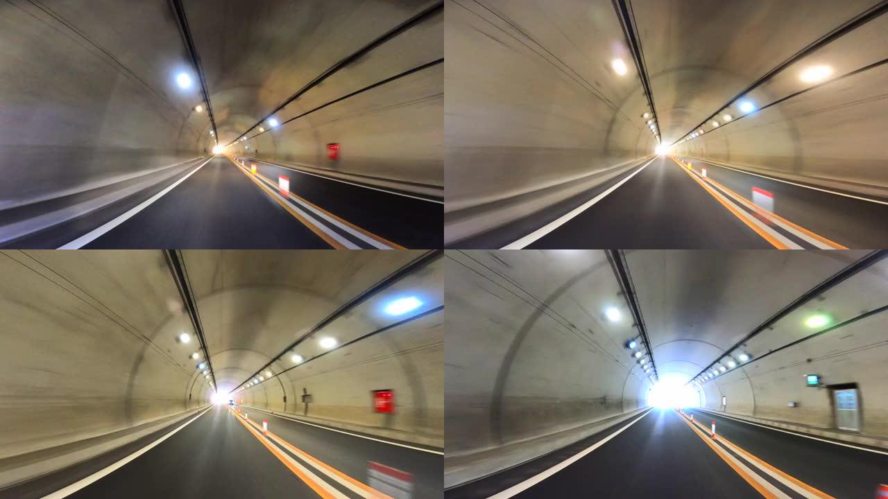 开车穿过高速公路隧道。高速公路双向隧道入口。隧道尽头的光
