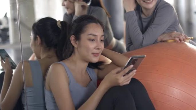 4k亚洲运动女性使用手机进行社交媒体或在健身馆在线购物。