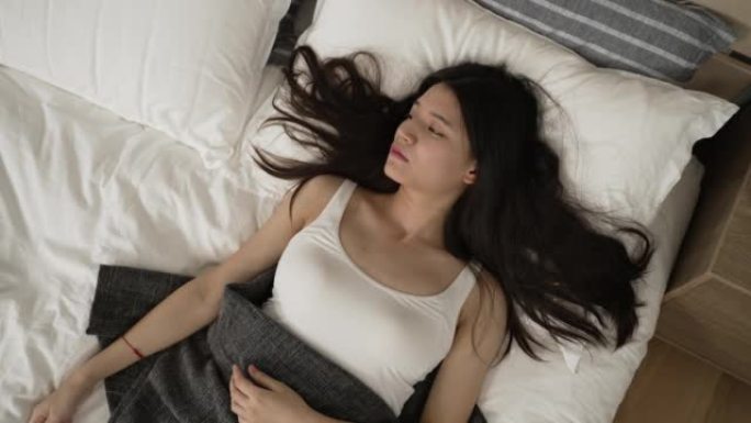 从顶级亚洲年轻女子的视角来看，荷兰的角度从充足的睡眠中自然醒来，在家里一个宁静的早晨，她在床上面带微