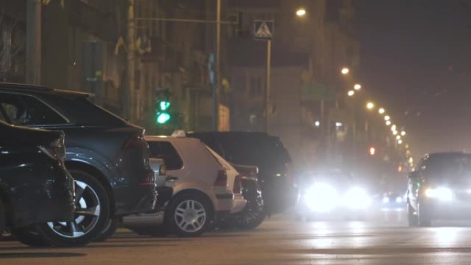 夜间关闭路边停放的汽车，城市街道上行驶的车辆的交通信号灯视野模糊。