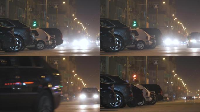 夜间关闭路边停放的汽车，城市街道上行驶的车辆的交通信号灯视野模糊。