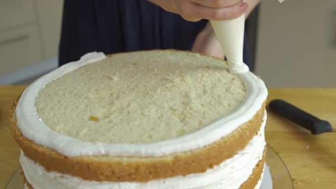 女人用白色奶油和饼干制作甜蛋糕的特写镜头。