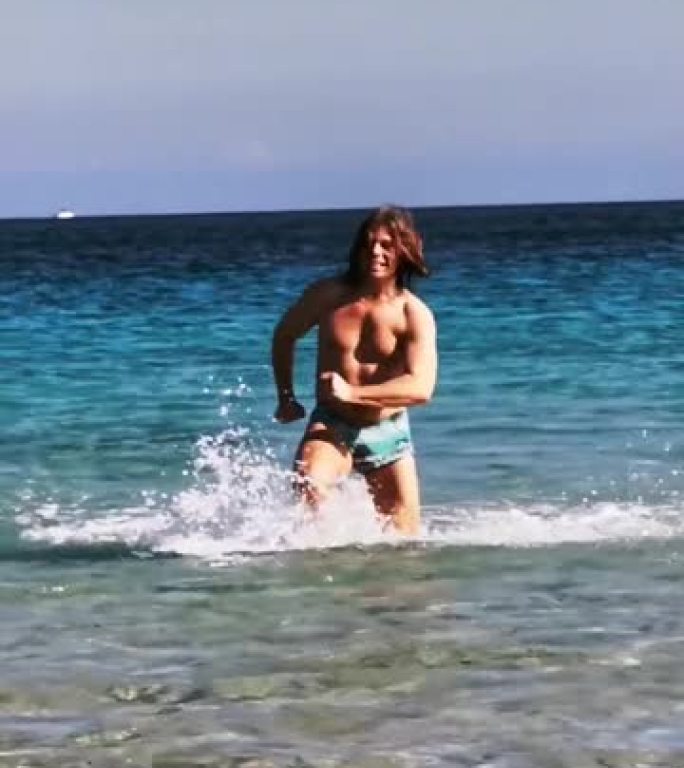 阳光明媚的日子，金发男子在海上奔跑，从蓝色到海滩。在西西里。