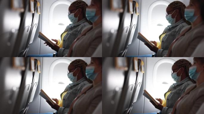 一名非洲成年女性戴着口罩在飞机上看书，以应对新冠肺炎疫情