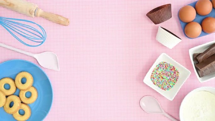 烤盘中的食材和饼干出现在柔和的粉红色背景上，带有空笔记本的食谱。停止运动平铺
