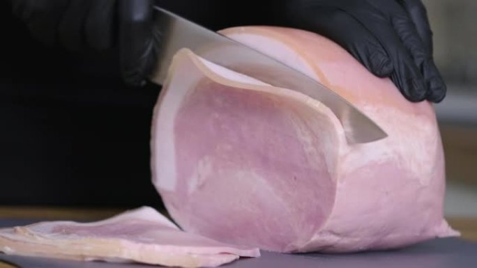 猪油熏火腿。用刀将传统火腿在砧板上切成碎片。薄片肉。美食小吃和烹饪的概念。持刀男子正在切西班牙猪腿火