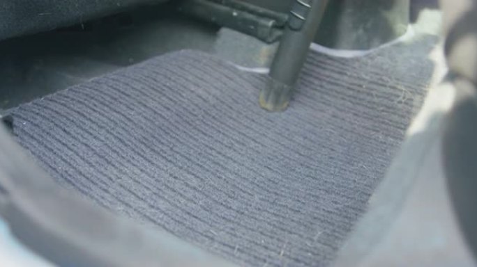洗车服务专家清洁车厢内肮脏的灰色纺织地毯，试图用真空吸尘器去除狗羊毛