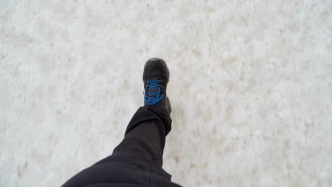 冬天，一个穿着黑色靴子的男人的腿在雪地里行走。视点视频。