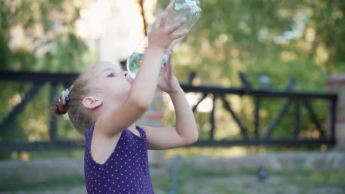 小女孩喝水大塑料瓶夏日公园