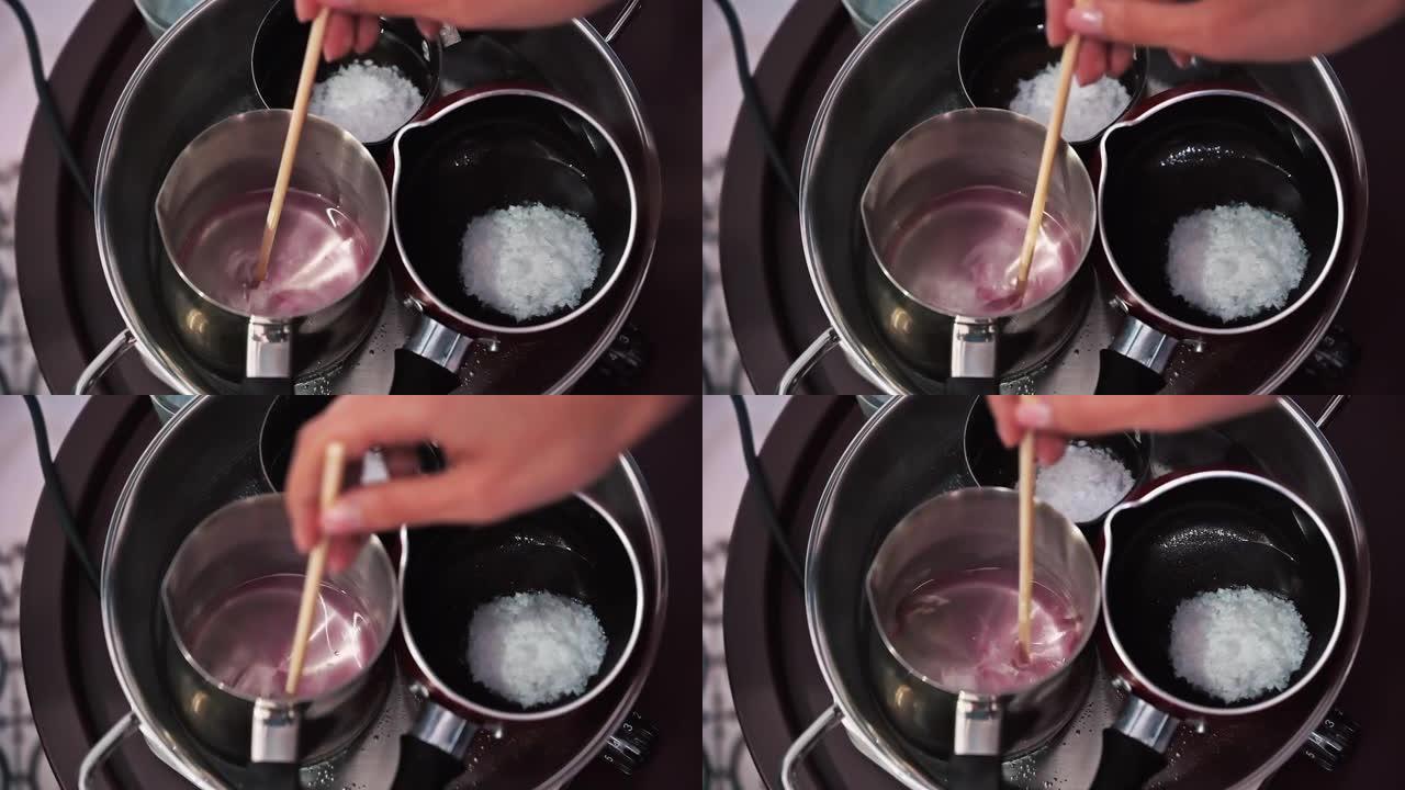 手工制作蜡烛，女性手在锅中混合熔化的蜡。慢动作