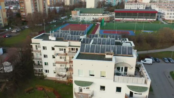 无人驾驶飞机在屋顶上安装太阳能电池板的多公寓住宅楼上拍摄，为房屋提供来自太阳的可再生能源