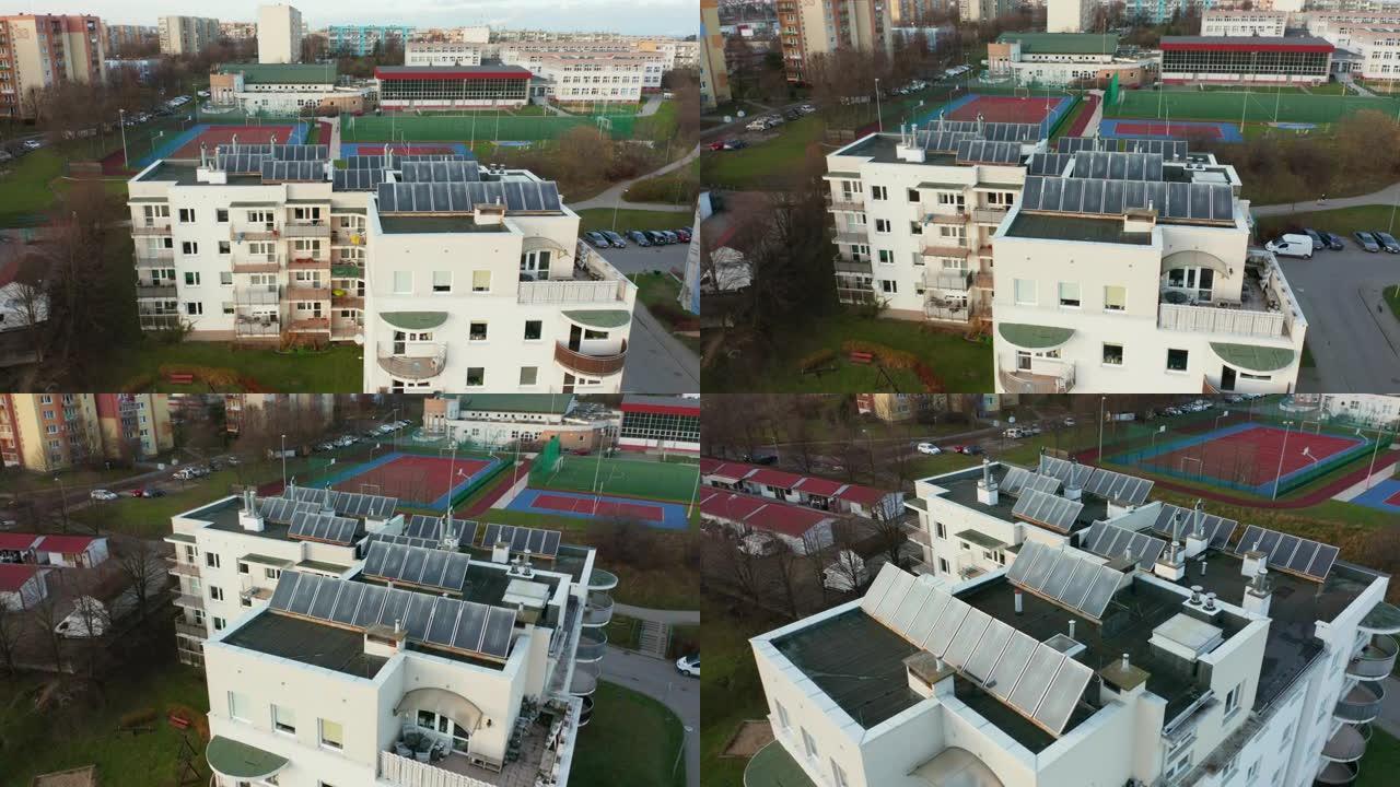 无人驾驶飞机在屋顶上安装太阳能电池板的多公寓住宅楼上拍摄，为房屋提供来自太阳的可再生能源