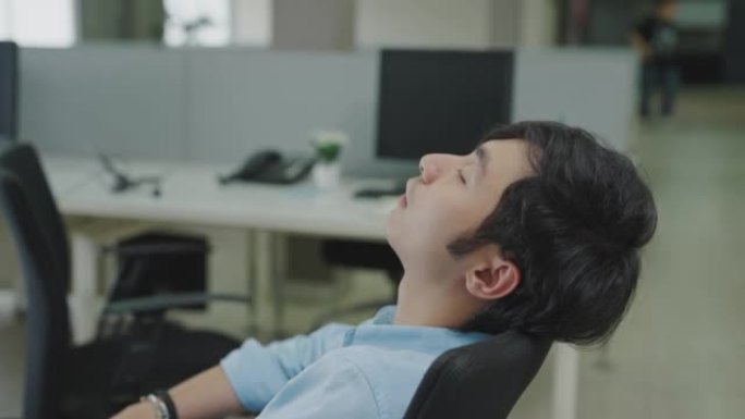 亚洲男性上班族睡在办公室的椅子上。