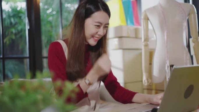 一名年轻的亚洲女性正在使用笔记本电脑与消费者交流，在她家的客厅里在线销售产品。