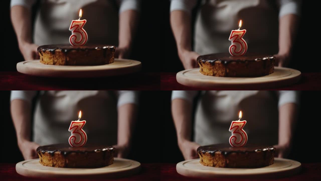 穿着厨房围裙的年轻女子将自制的巧克力蛋糕或带有3号蜡烛的馅饼放在家里的桌子上。三岁，庆祝生日概念