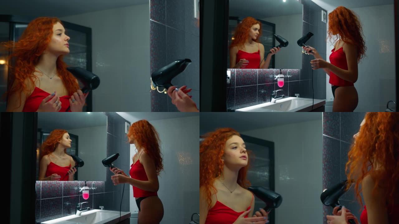 女人在浴室用吹风机吹干红头发