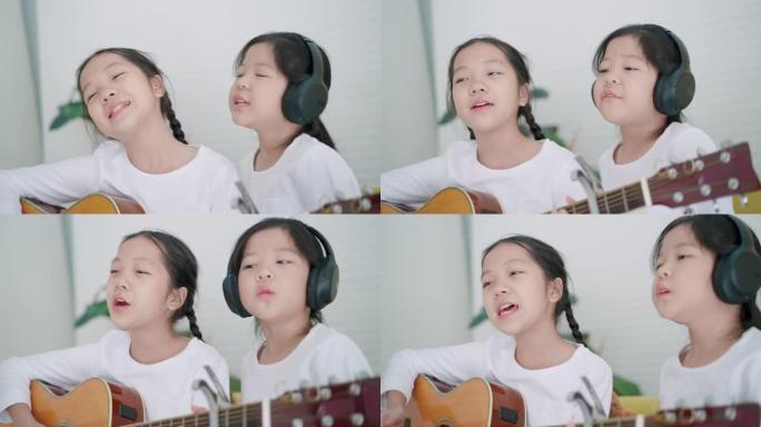 快乐时光在音乐教室里，7岁的小学老年亚洲女孩表演弹吉他，和5岁的小学老年亚洲女孩一起坐着，戴着无线耳