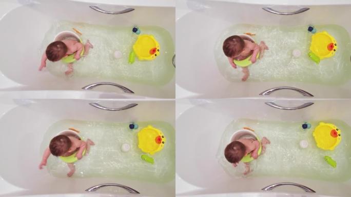 快乐的蹒跚学步的男婴坐在椅子上沐浴在白色的浴缸里。孩子在大浴缸里玩水，孩子九个月大