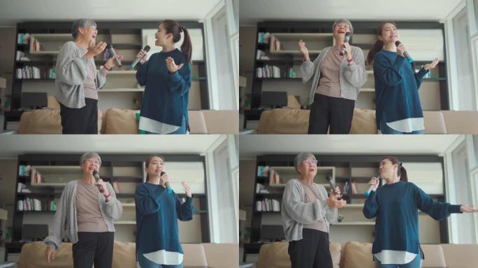 亚洲华裔高级女子在周末休闲活动中与女儿在客厅唱歌卡拉ok跳舞