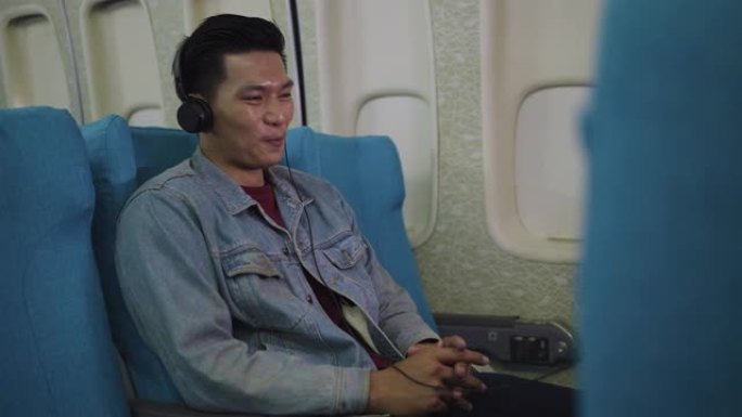 亚洲旅客旅客在飞机上看电影或在飞行中戴着耳机听音乐