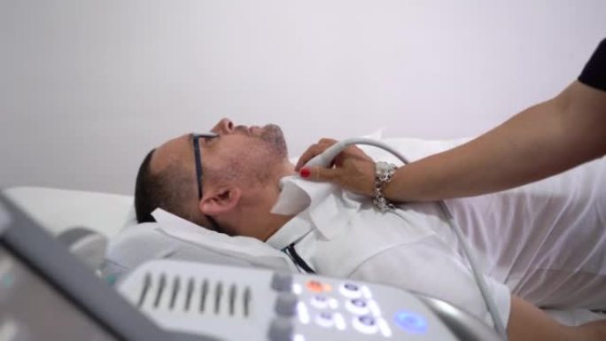 使用超声扫描仪检查患者甲状腺的女医生