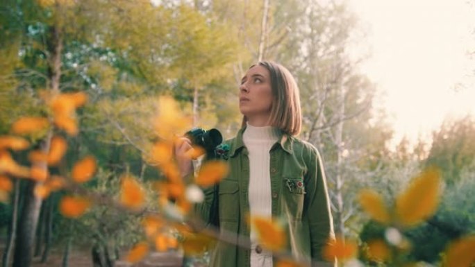 大自然中的女孩，用老式相机在日落时看着树木，中景，慢动作，手持。
