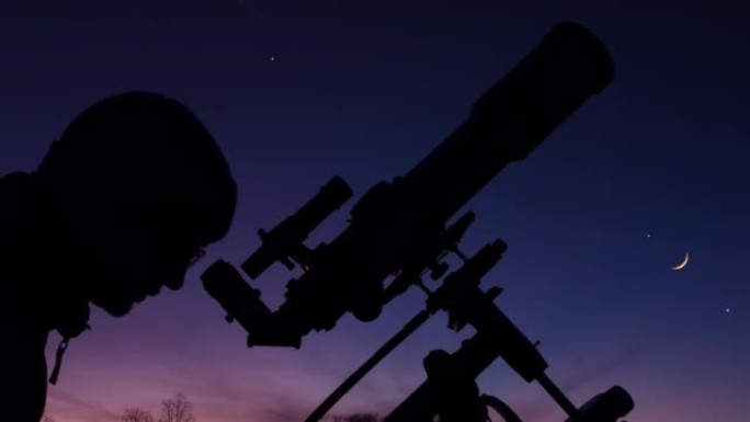 夜空下男人、望远镜和乡村的轮廓。