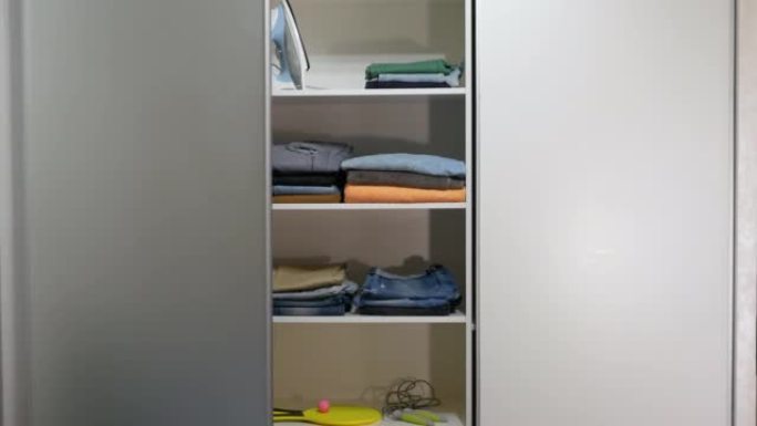 带衣服的衣柜。衣柜中的滑动门系统，隔间的滑动门打开和关闭系统。衣服的储物空间。当代衣柜