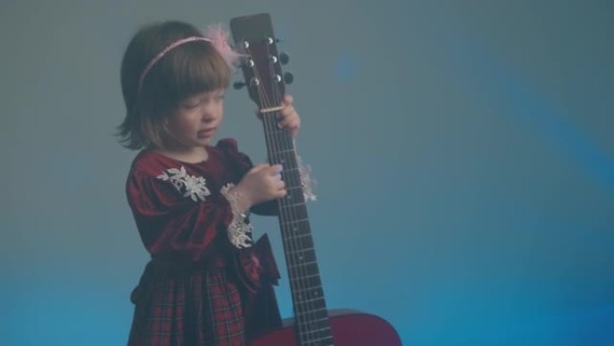 穿着复古连衣裙的小女孩像低音提琴一样弹着原声吉他