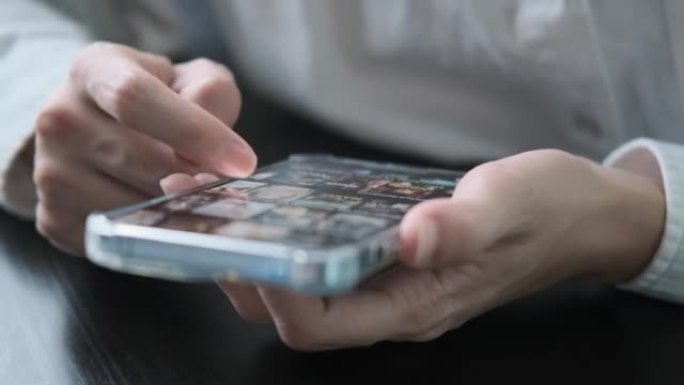 手机上的职业女性手指触摸滚动页面app。在互联网库中浏览电影视频以在线观看电影。