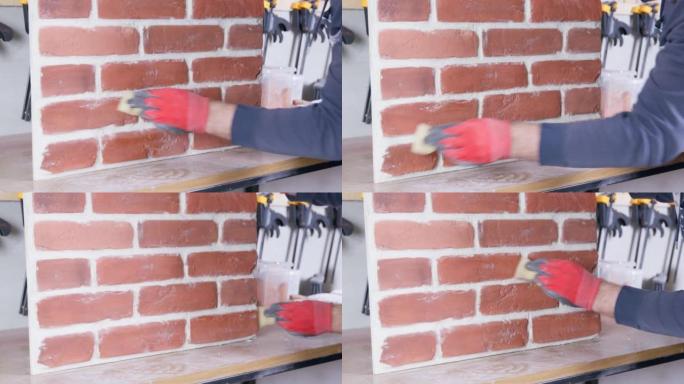 防护橡胶手套的工人用湿海绵擦拭仿制的砖砌元件，将其从建筑灰尘中清除。基于旧砖铸件的瓷砖制成的饰面材料