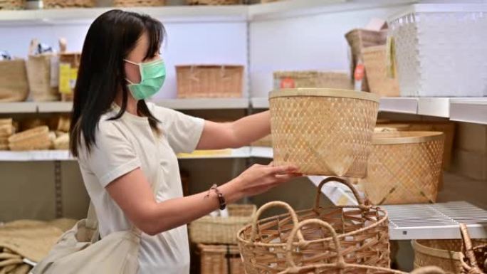 4k亚洲妇女戴着防护面具在家居用品商店选择柳条篮