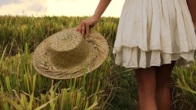 无忧无虑的女人戴着草帽走在稻田里